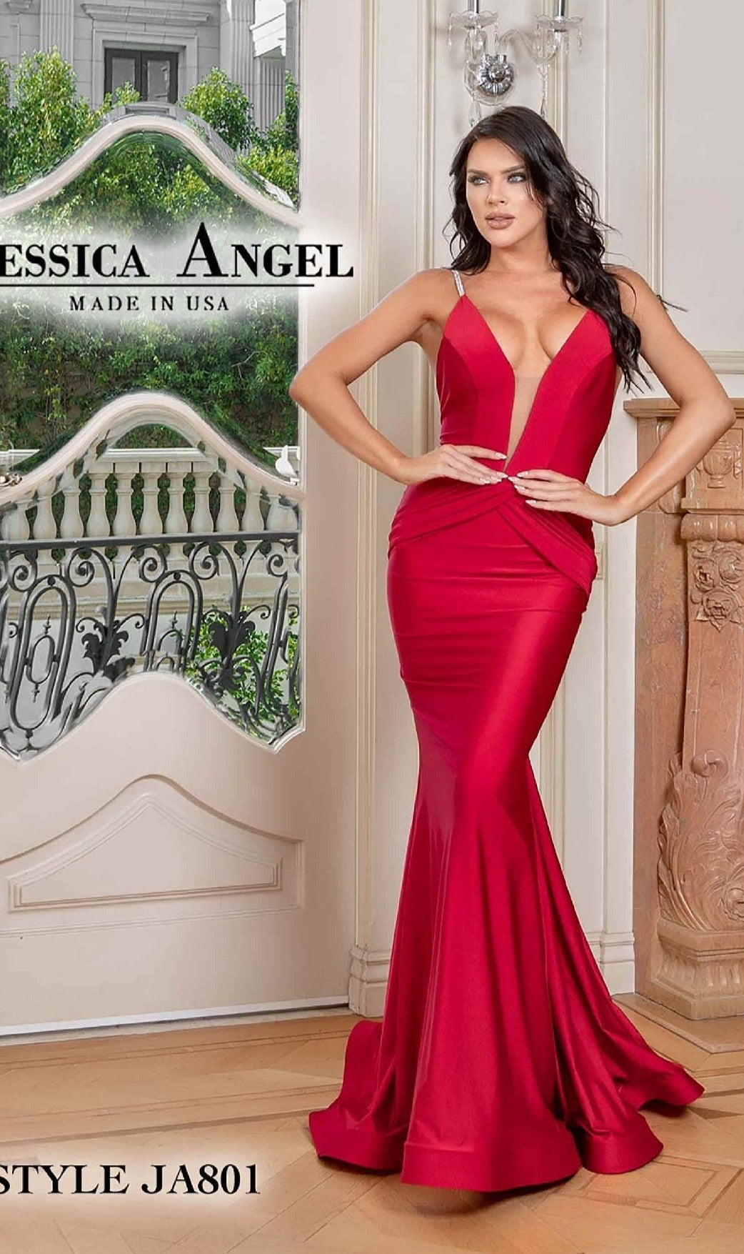 A woman wearing the Jessica Angel 801 Plunging V-Neck Long Prom Dress in deep red with a mermaid skirt stands indoors near a decorative white and wood railing.